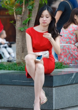 坐在花坛玩手机的红色短裙大白腿美足高跟鞋长腿美女图
